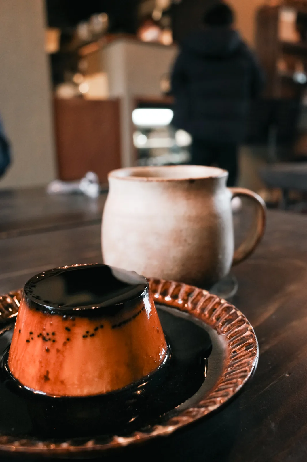 喫茶店のテーブルに置かれたプリンとマグカップ
